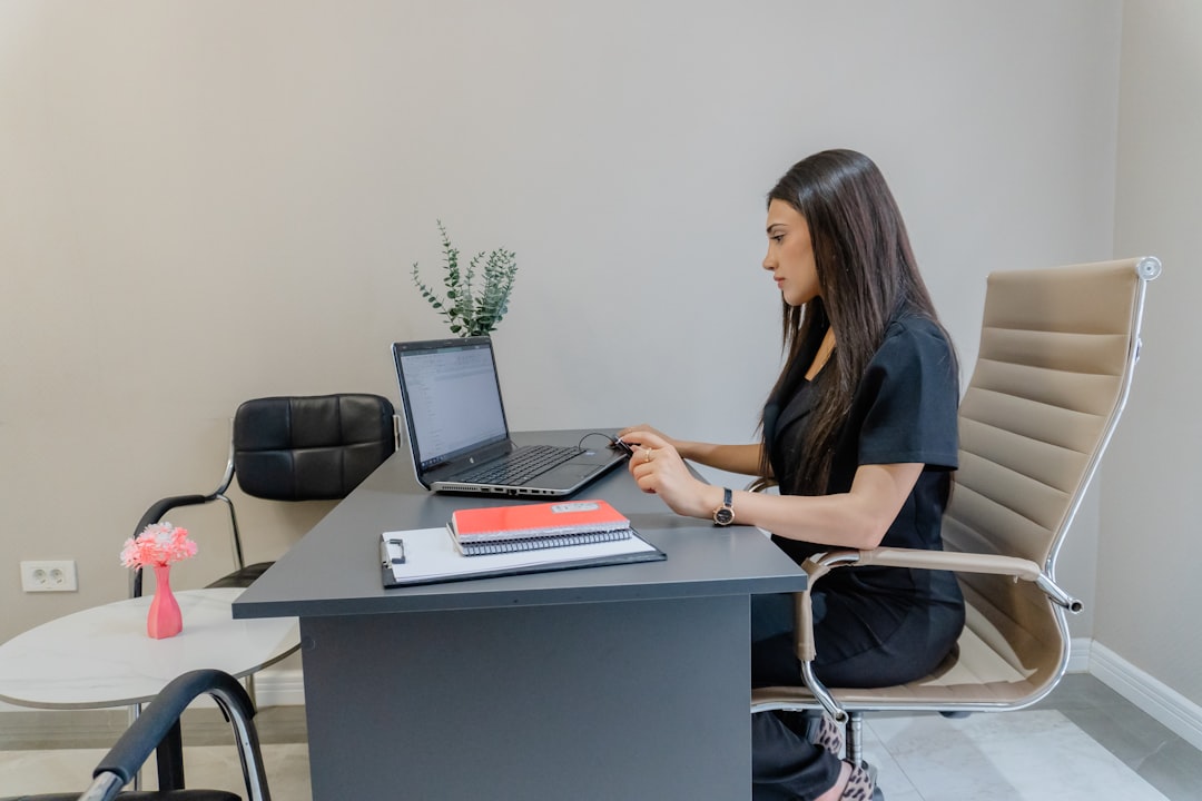 Woman working on laptop at desk in office.