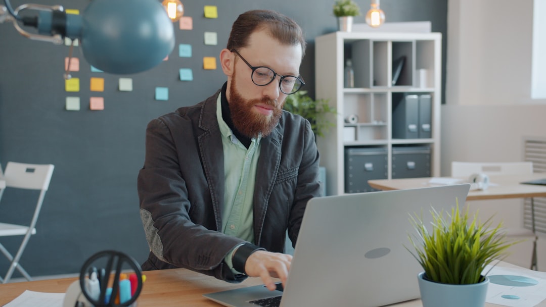 Man with beard working on laptop in office